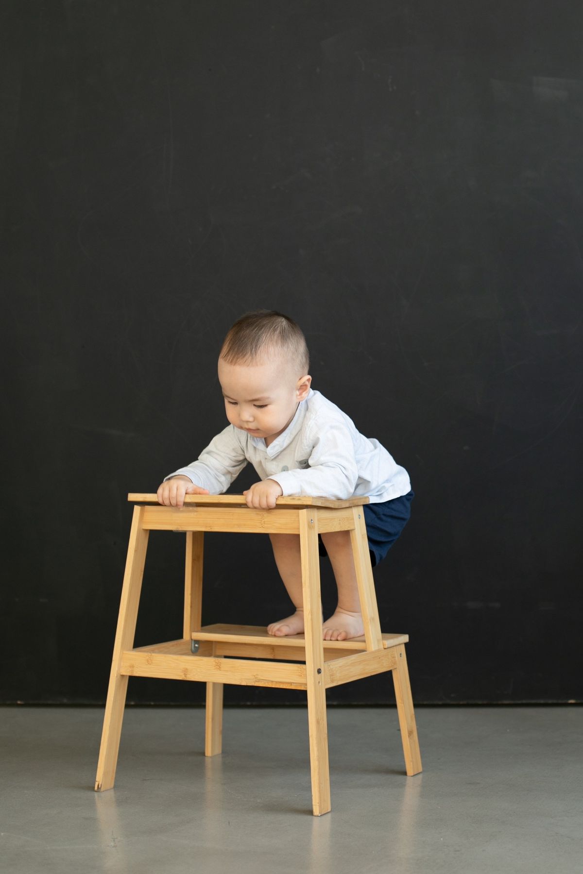木のスツールに手をかける小さな子ども(写真はイメージ)